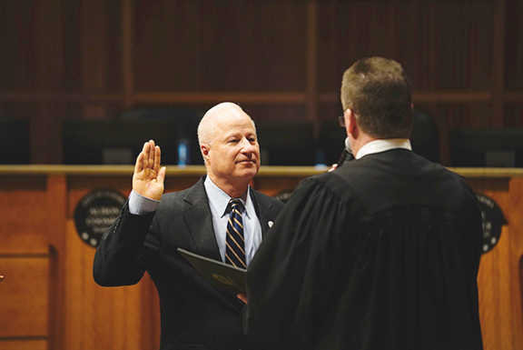 Mike Coffman wearing a suit and swearing on bible while being sworn into Congress